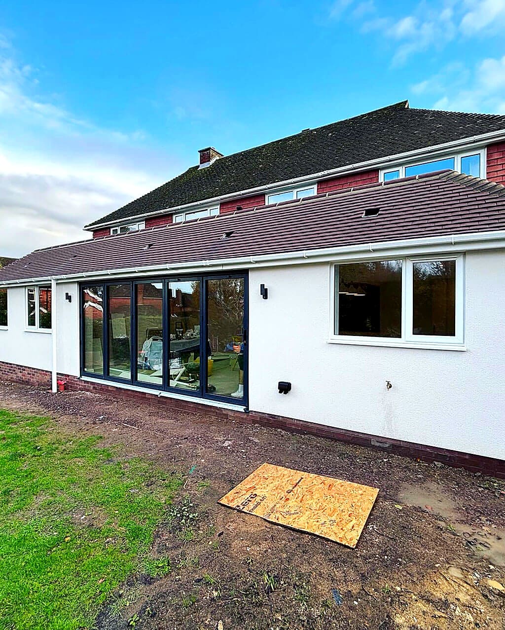 White rendered rear extension with five leaf anthracite bifold doors and a tiled roof