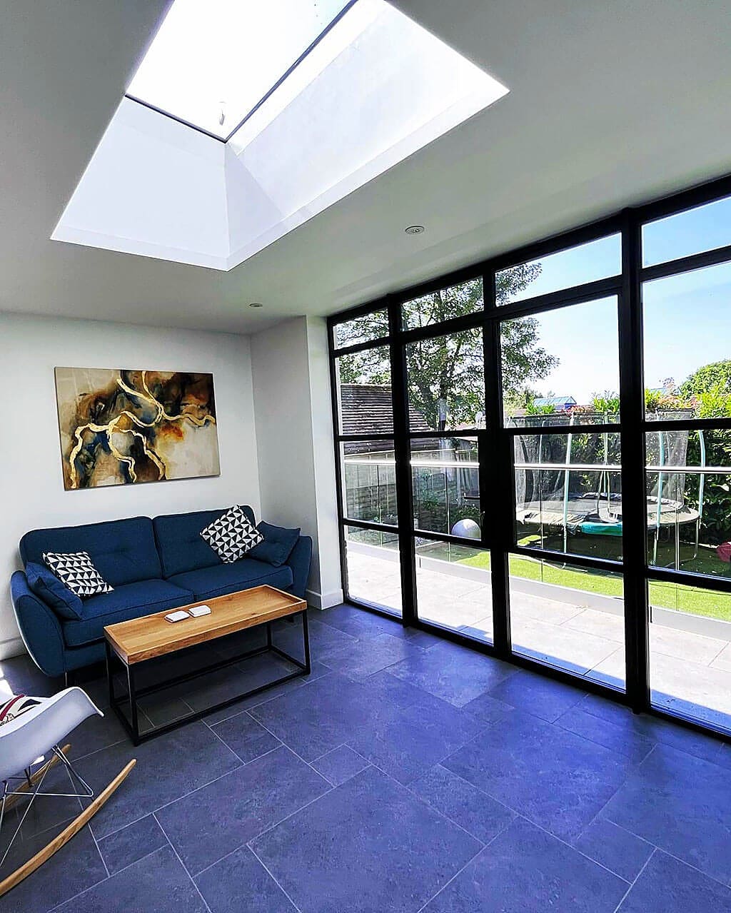 Garden room interior with a large roof lantern and a full height Crittall style glazed wall onto the garden