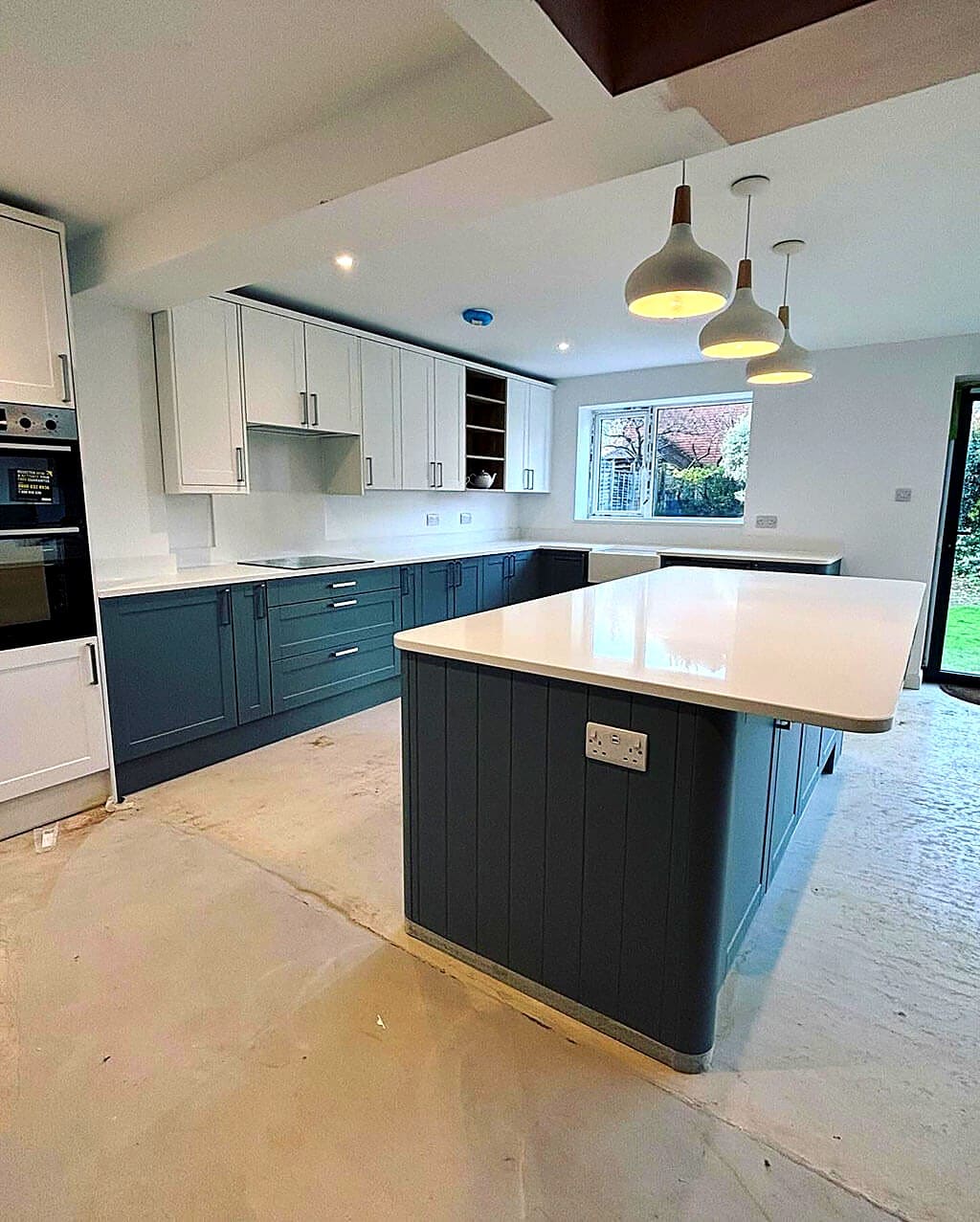 Newly fitted shaker kitchen with a large island, quartz worktop and pendant lighting